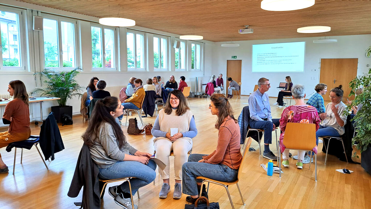 Weiterbildung in Gewaltfreier Kommunikation. Gruppe von Menschen machen eine Übung.